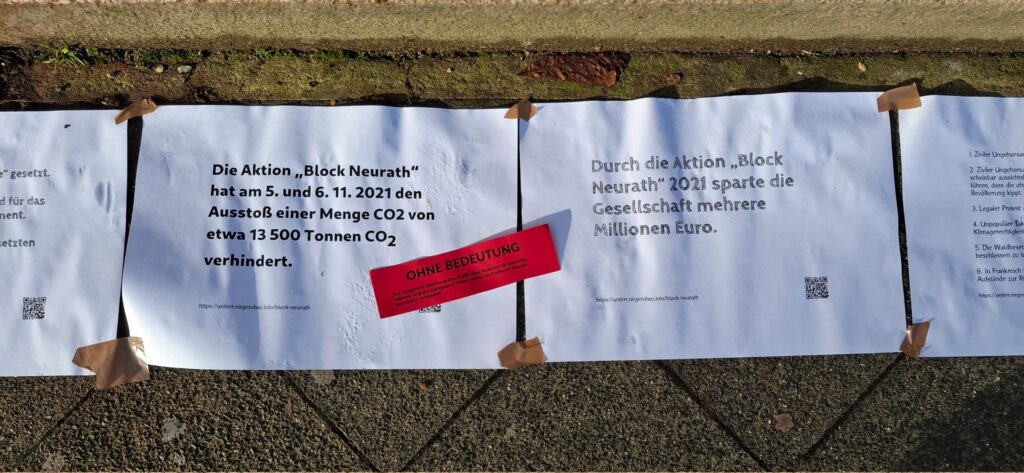 Aufgeklebte Plakate, Aufschrift auf einem "Die Aktion "Block Neurath hat am 5.und 6.11.2021 den Ausstoß einer Menge CO2 von etwa 13500 Tonnen CO2 verhindert."