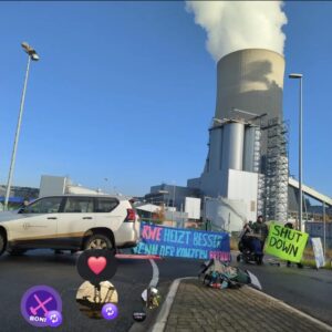 RWE heizt besser wenn der Konzern brennt steht auf einem blauen Transparent vorm Kohlekraftwerk, links im Bild ist ein Auto zu sehen.